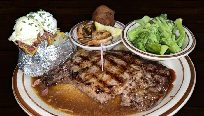 Choice or better hand cut and aged open flame grilled steaks at Samuel's Roadhouse restaurant in Crestview Florida served with loaded baked potato, au jus, and broccoli