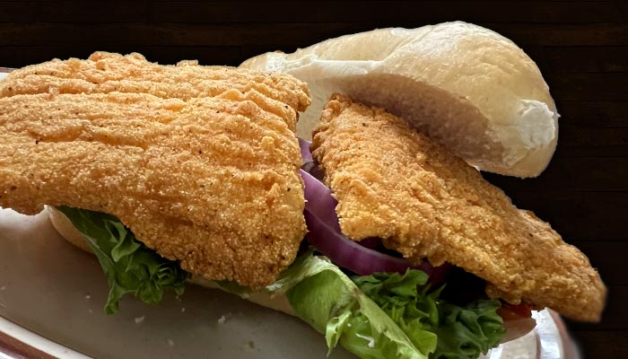 Lightly breaded and fried golden chicken or fish sandwich at Samuel's Roadhouse restaurant in Crestview topped with bacon, cheese, lettuce, onion and tomato